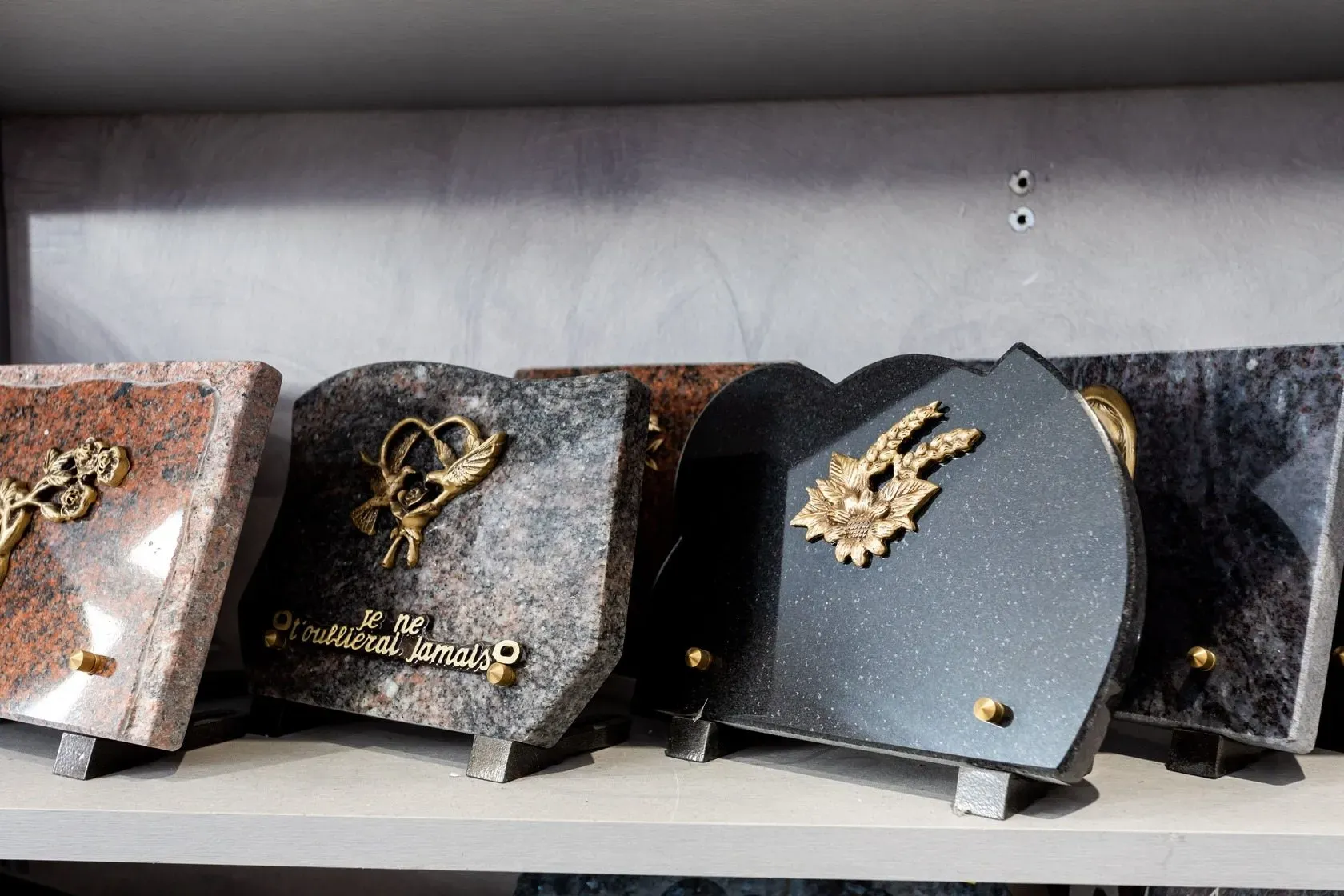 Plaques funéraires en granit décorées de motifs dorés exposées en magasin.
