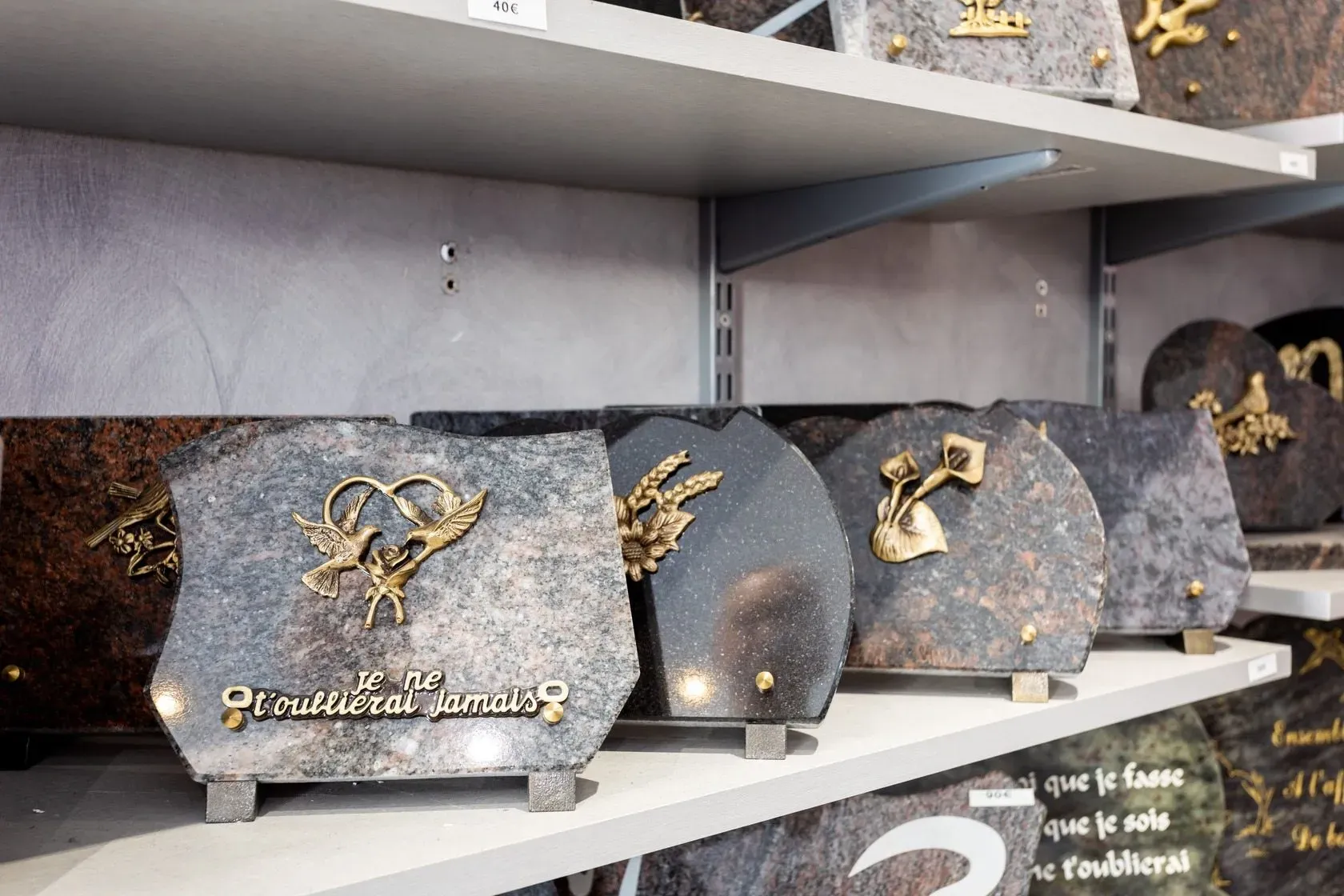 Des plaques funéraires personnalisées exposées sur des étagères d'un magasin.