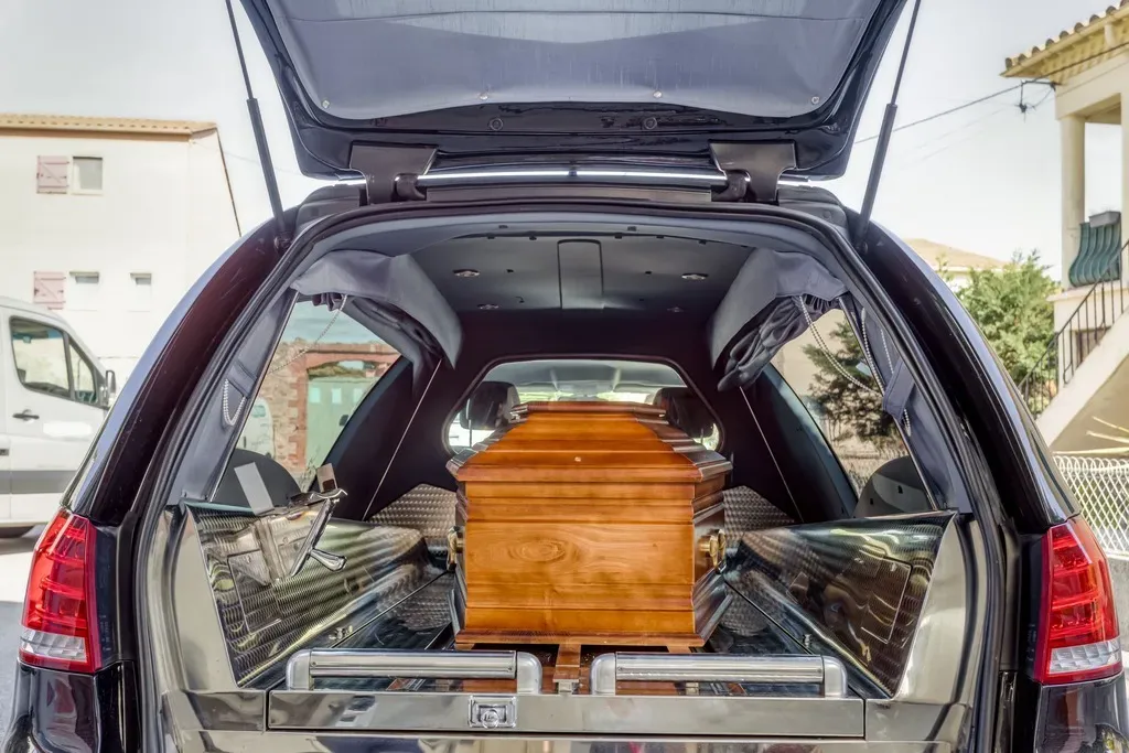 Vue intérieure d'un corbillard avec un cercueil en bois installé sur le plateau.